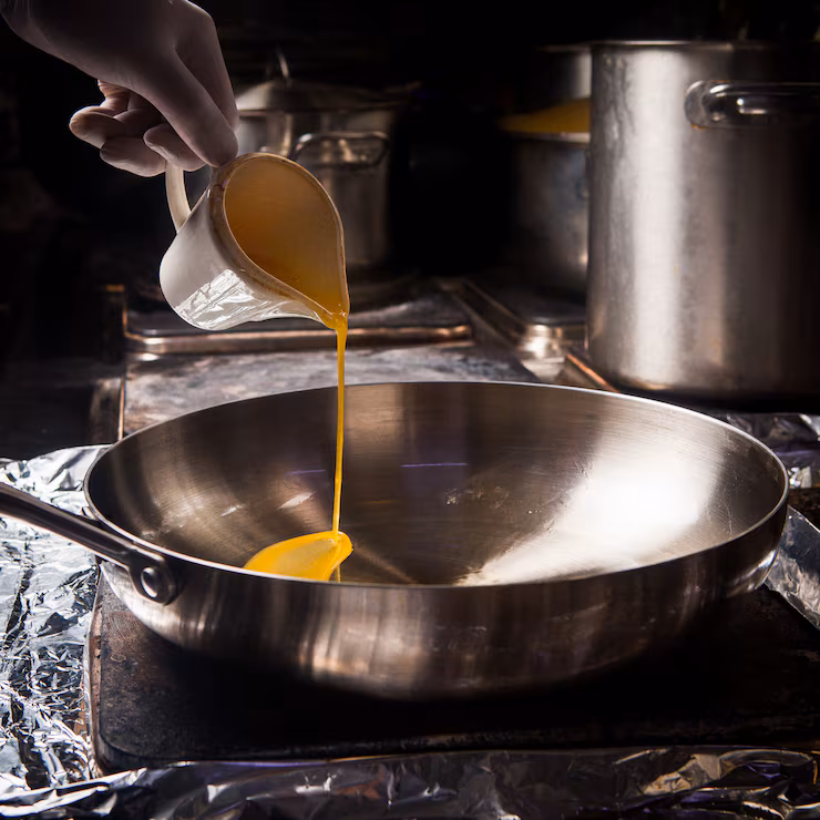 side view pan with melted butter human hand — how to make desi ghee article image